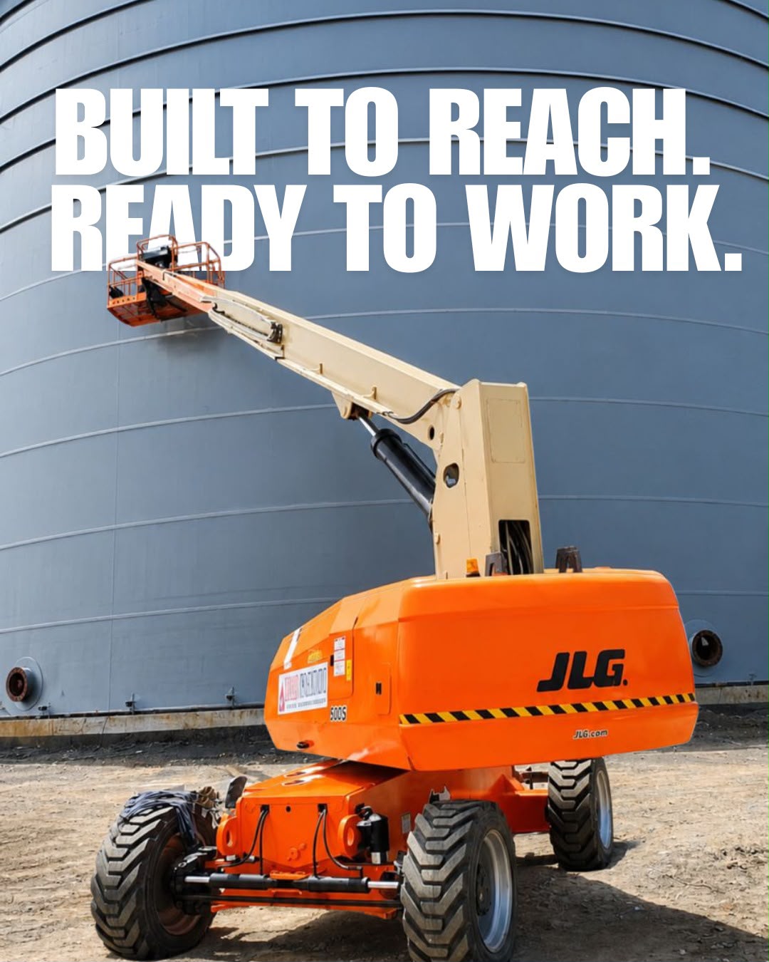 Orange boom lift working beside an industrial facility